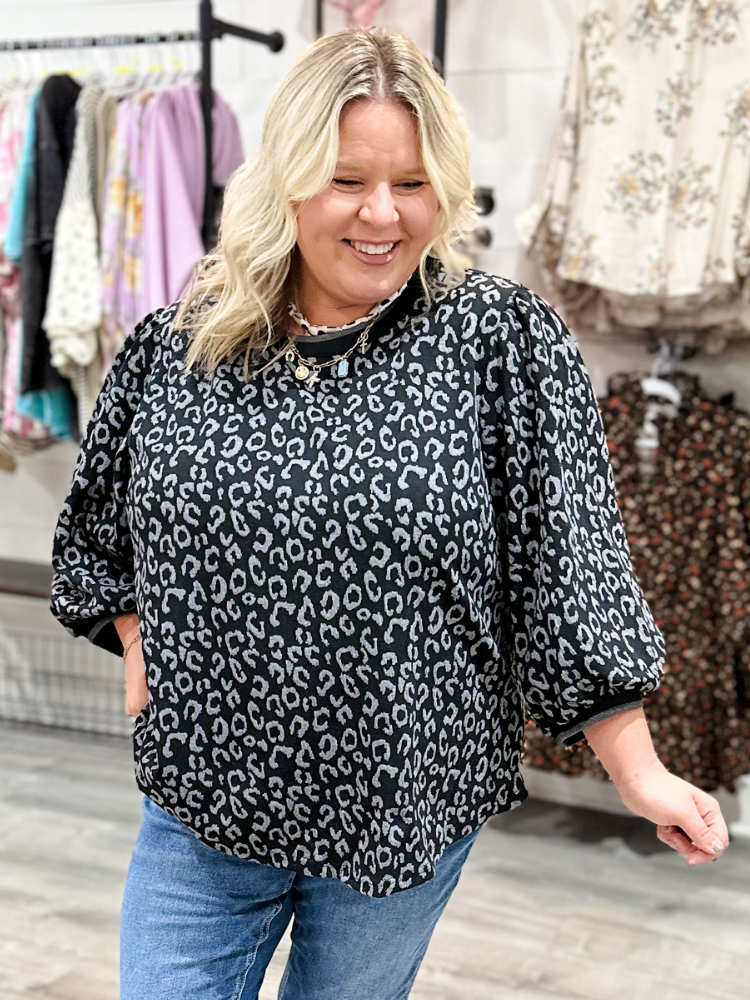 Woman wearing a black leopard print top in a clothing store.
