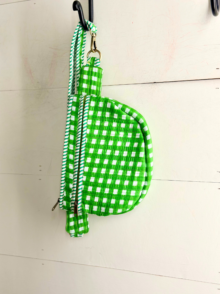 Green and white checkered dog leash on a hook against a light wooden floor.